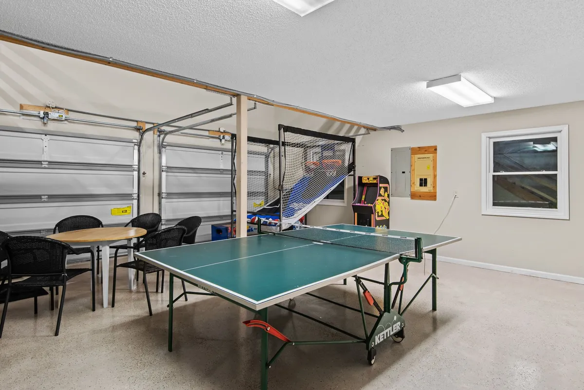 A closer look at the game room's ping pong table and arcade game, with a seating area for relaxing between rounds. The casual setting encourages friendly competition and group fun, emphasizing the room's versatility for different ages and interests.