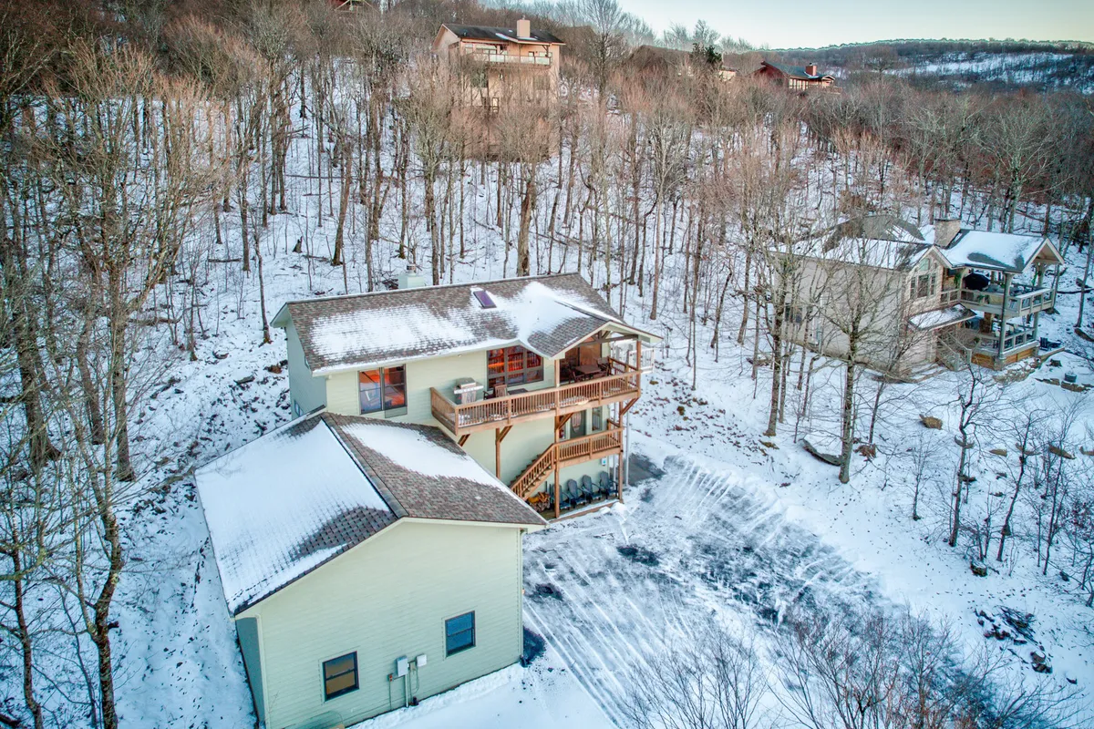 The exterior of the house surrounded by snow-covered ground and tall trees. The home appears nestled in nature, evoking a sense of adventure and proximity to Beech Mountain's trails and slopes.