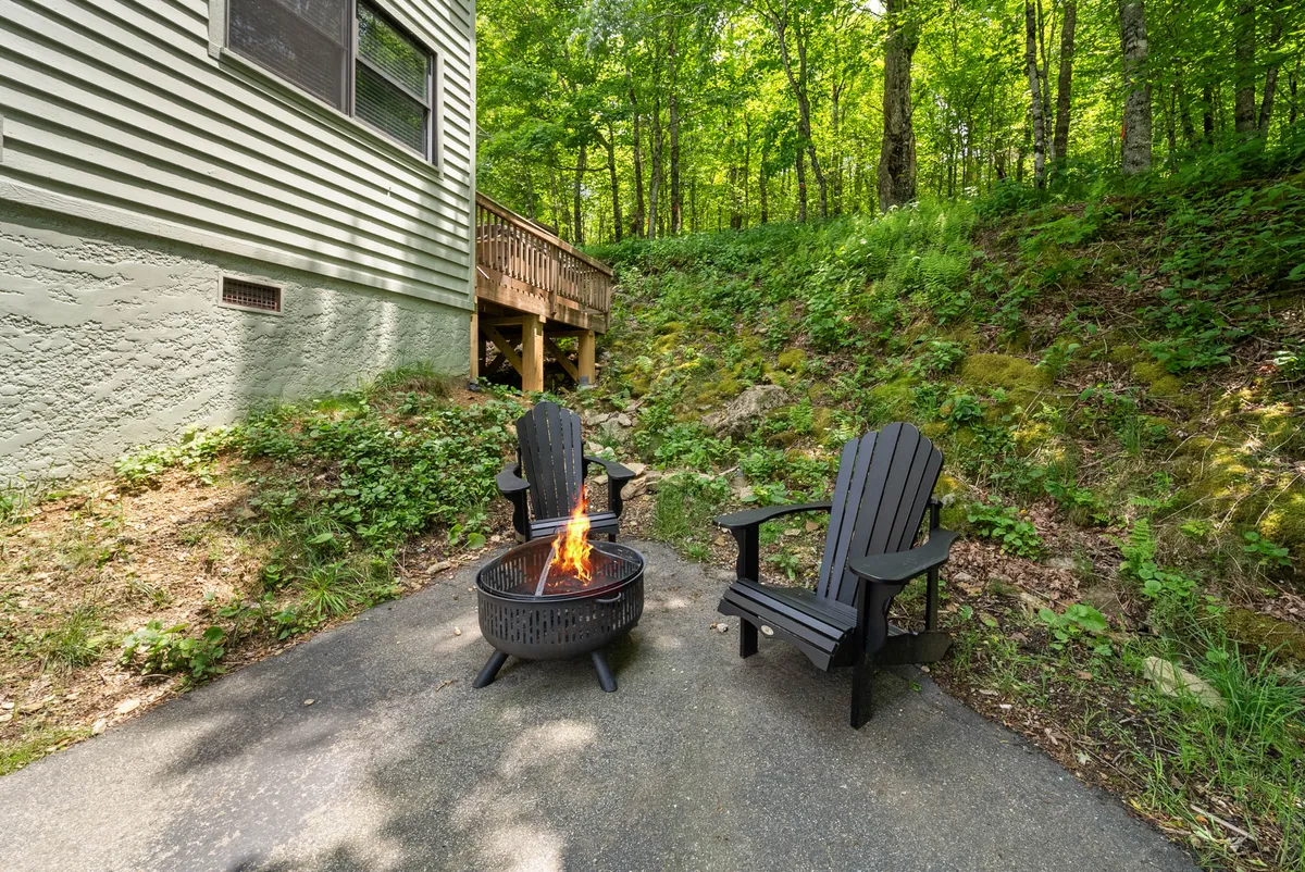A fire pit encircled by inviting Adirondack chairs, set against a backdrop of lush greenery. The setup suggests warmth, camaraderie, and evenings spent sharing stories under the stars.